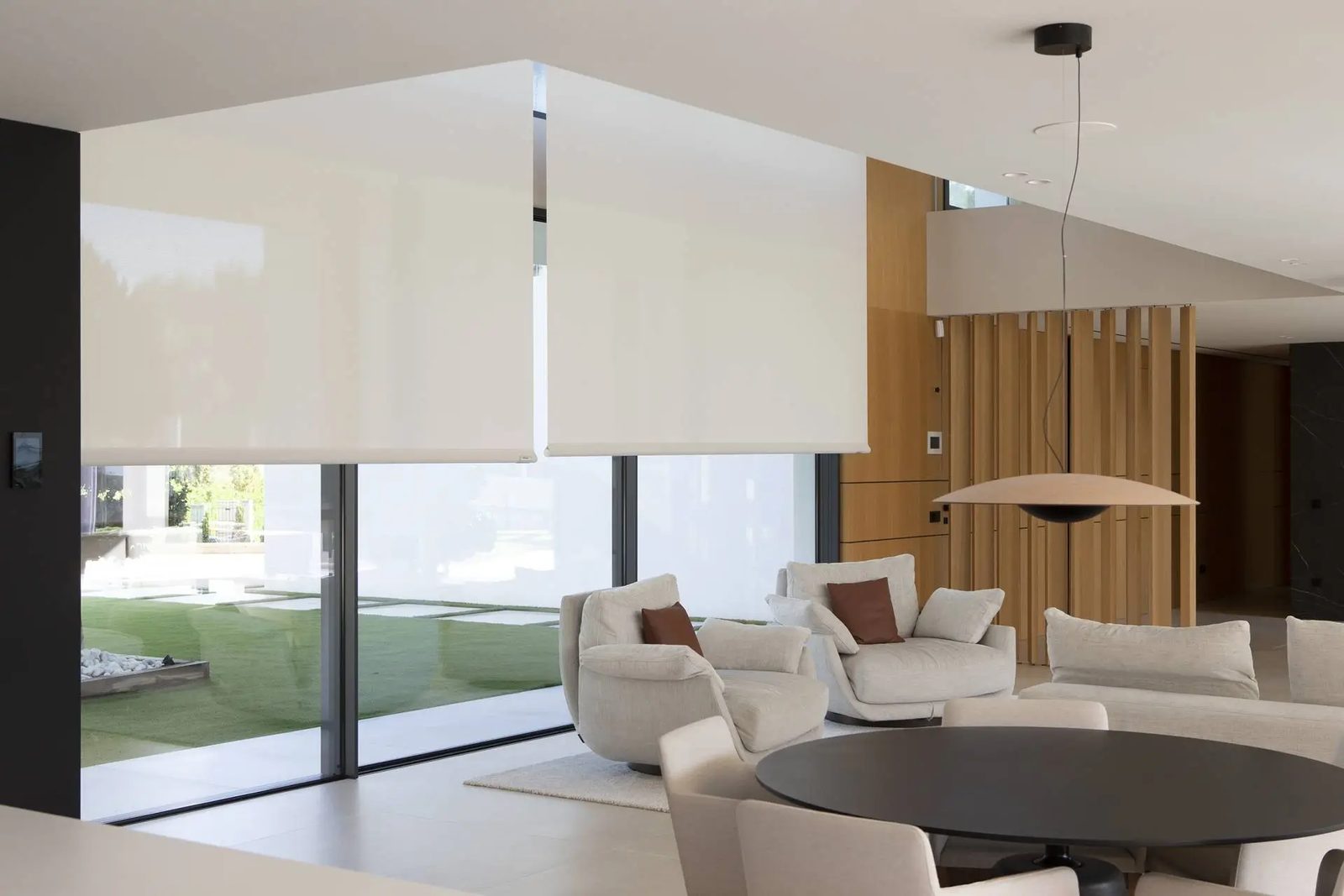 Estores enrollables en salón de diseño con grandes ventanales y jardín exterior