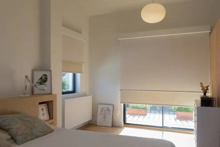 Dormitorio con enrollables en crema y acceso a terraza