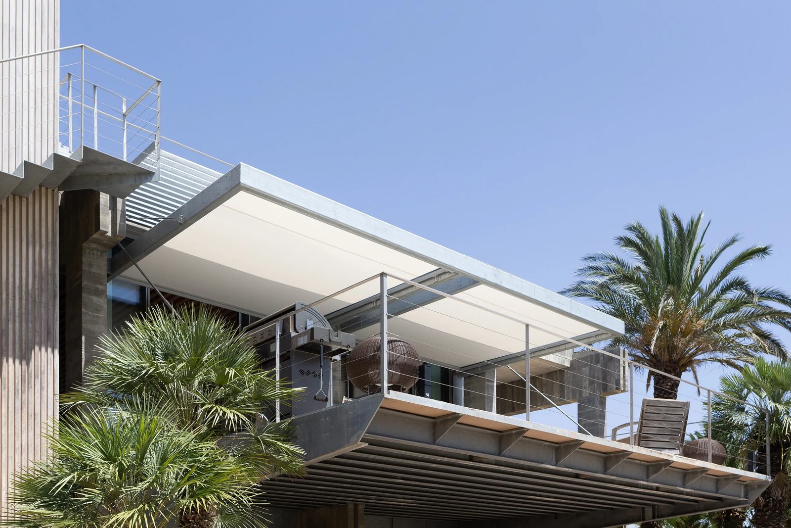 Veranda Bandalux desplegada sobre terraza con estructura de hormigón y palmeras