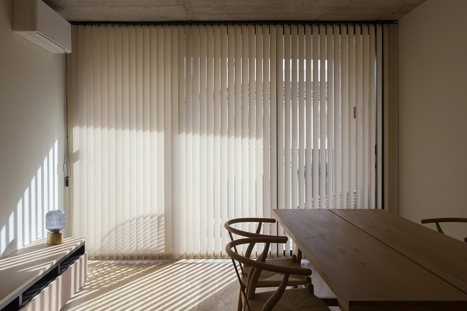 Verticales crema en comedor nórdico con sombras geométricas en el suelo